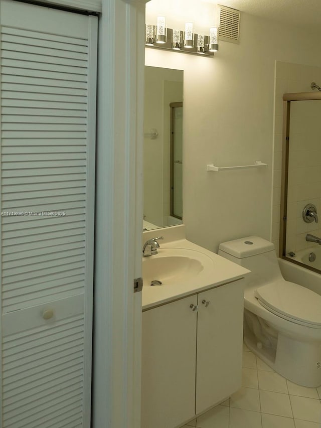 full bathroom with bath / shower combo with glass door, toilet, vanity, and tile patterned flooring