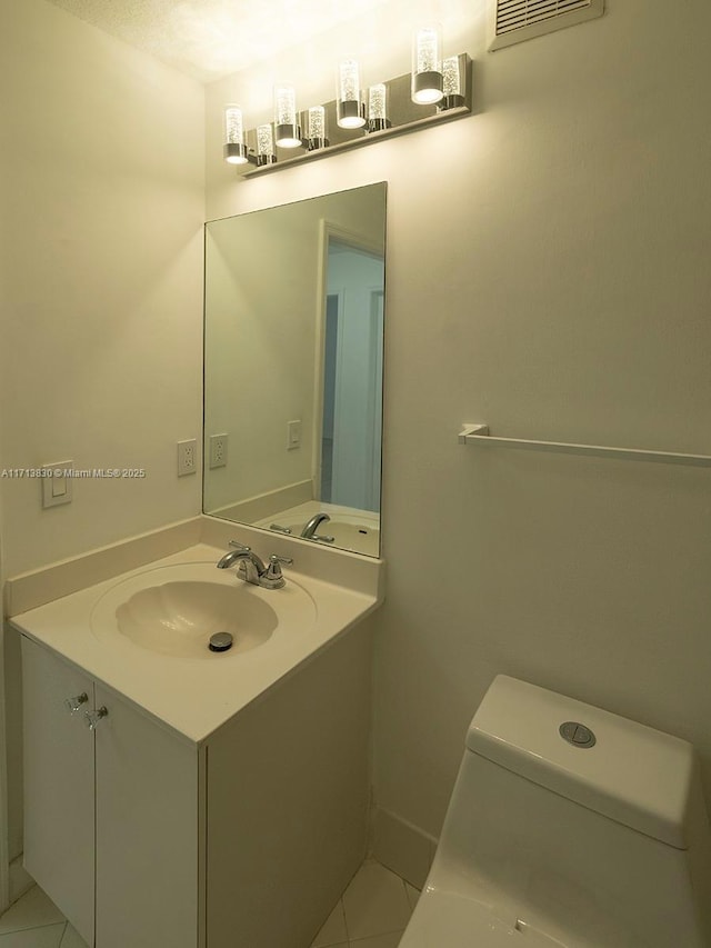 bathroom with toilet, vanity, and tile patterned floors