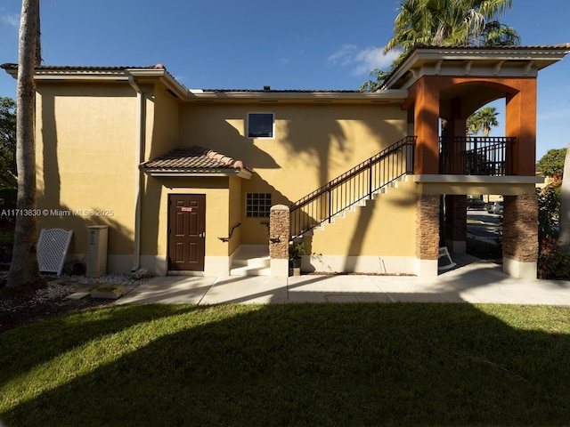 back of property with a lawn and a patio