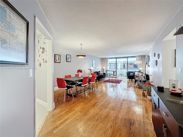 dining area featuring a textured ceiling, light hardwood / wood-style floors, and floor to ceiling windows