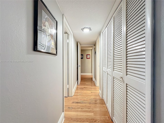 hall featuring light hardwood / wood-style floors and a textured ceiling