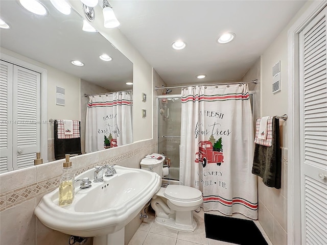 bathroom featuring tile patterned floors, sink, a shower with shower curtain, toilet, and tile walls