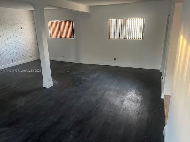 basement featuring dark hardwood / wood-style flooring and brick wall