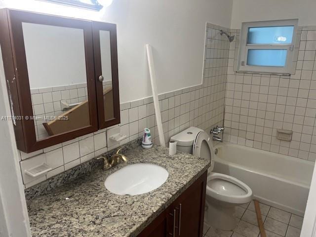 full bathroom featuring tile walls, tiled shower / bath combo, vanity, tile patterned floors, and toilet