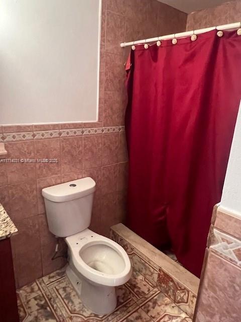 bathroom featuring tile patterned floors, toilet, tile walls, and vanity