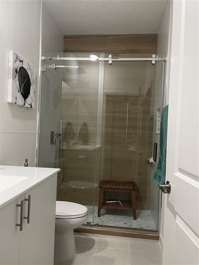 bathroom with tile patterned floors, vanity, toilet, and a shower with door