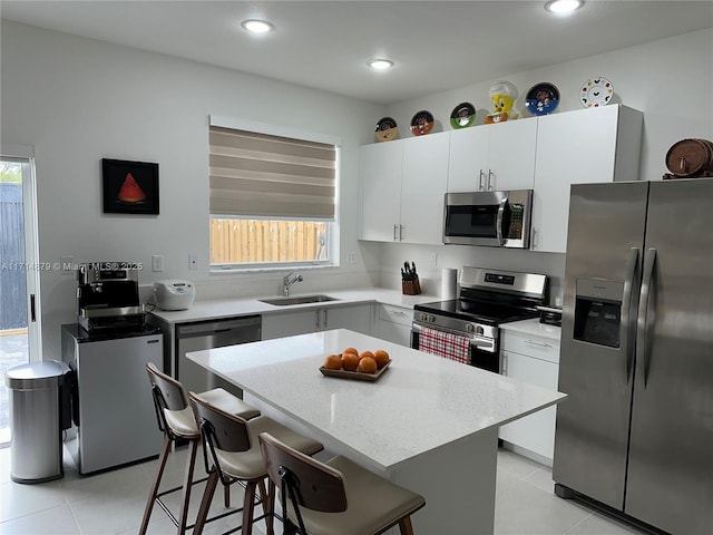 kitchen featuring sink, stainless steel appliances, a kitchen island, a kitchen bar, and white cabinets