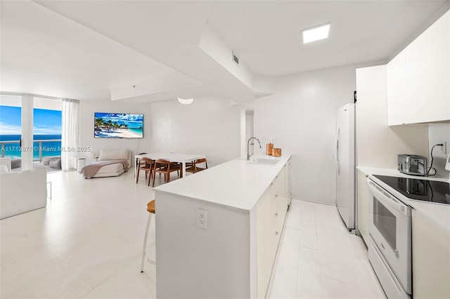 4779 Collins Ave Unit 3108, Miami Beach, FL 33140 - kitchen featuring a peninsula, white appliances, open floor plan, light countertops, and a breakfast bar area