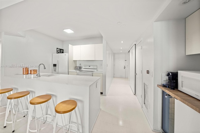 4779 Collins Ave Unit 3108, Miami Beach, FL 33140 - kitchen featuring white appliances, a kitchen bar, white cabinetry, a peninsula, and recessed lighting