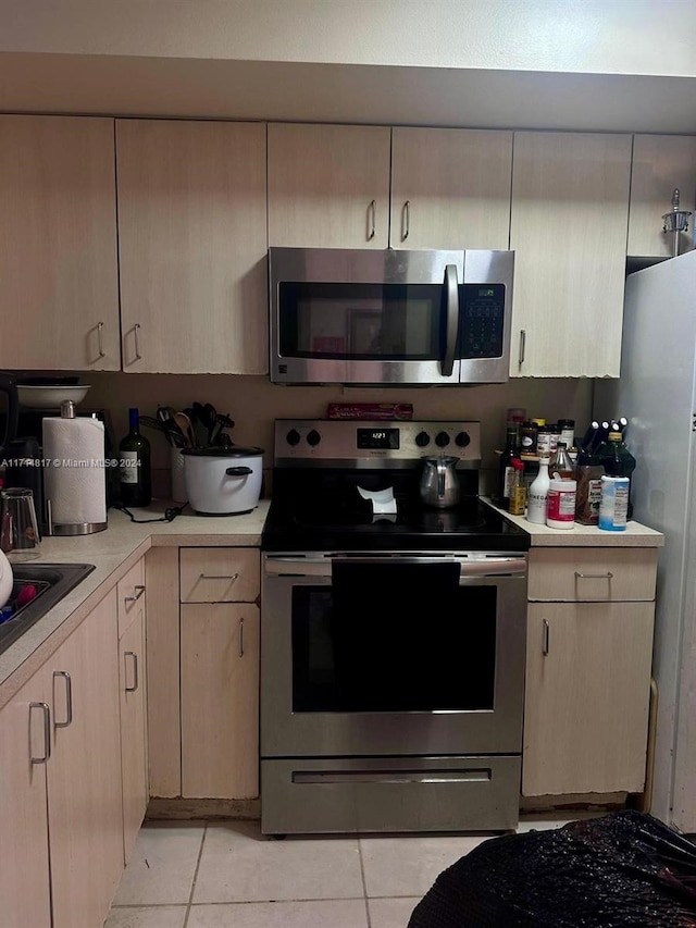 kitchen with light tile patterned floors, light brown cabinetry, and appliances with stainless steel finishes