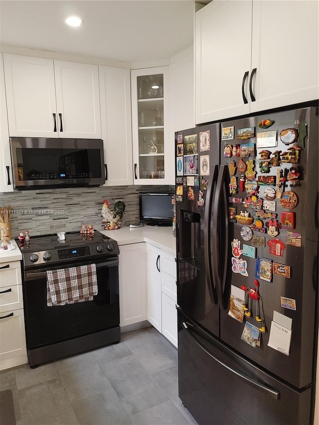 kitchen with black refrigerator with ice dispenser, white cabinetry, and range with electric cooktop