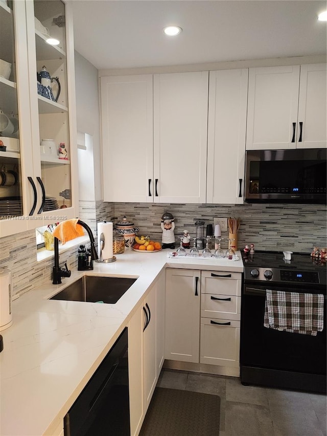 kitchen with sink, white cabinetry, black appliances, and tasteful backsplash