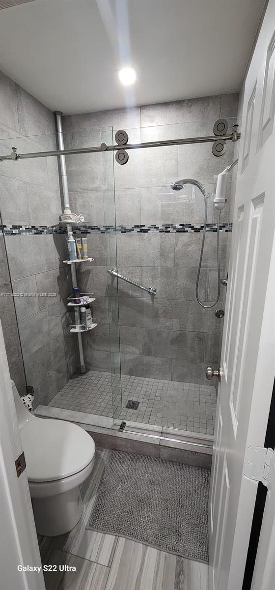 bathroom with a shower with shower door and toilet