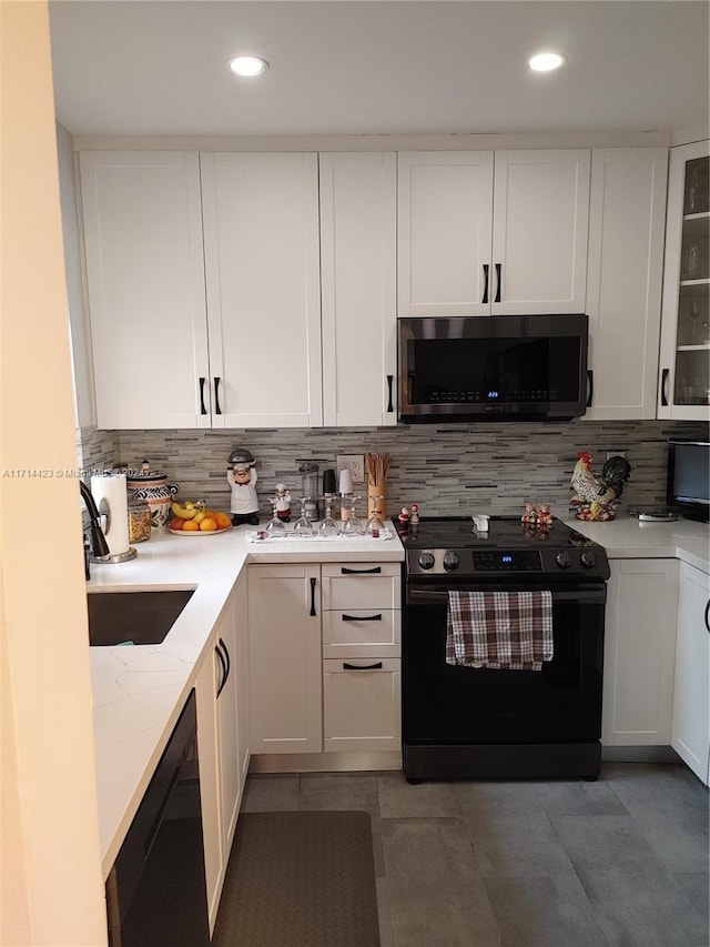 kitchen with white cabinetry, black appliances, and tasteful backsplash