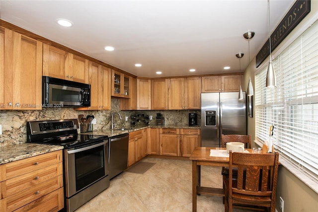 kitchen with light stone countertops, sink, stainless steel appliances, decorative light fixtures, and light tile patterned floors