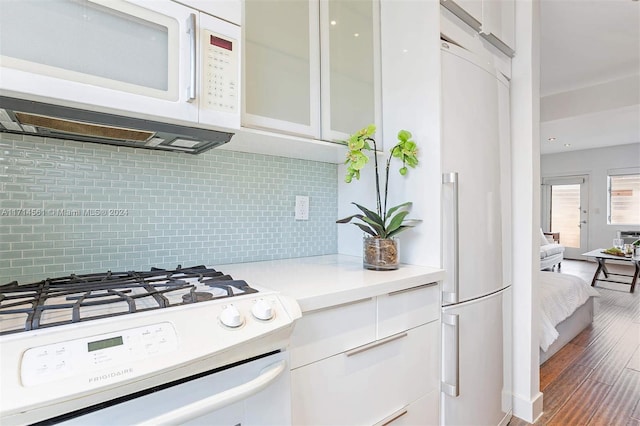 kitchen with white cabinets, white appliances, hardwood / wood-style flooring, and tasteful backsplash