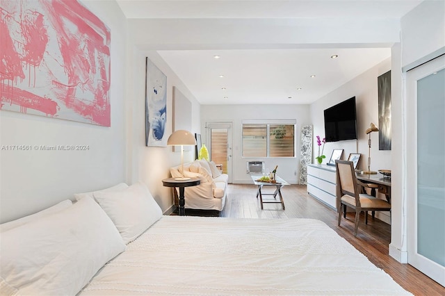 bedroom with hardwood / wood-style floors and an AC wall unit