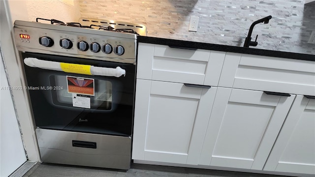 interior details with backsplash, white cabinetry, and stainless steel range oven