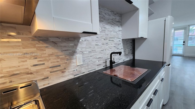 kitchen with backsplash, white cabinetry, and sink