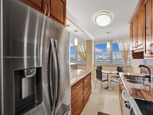 kitchen featuring light stone countertops, stainless steel refrigerator with ice dispenser, ornamental molding, sink, and decorative light fixtures