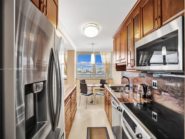 kitchen with light stone countertops, tasteful backsplash, stainless steel appliances, sink, and pendant lighting