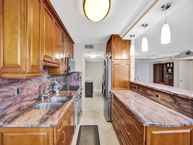 kitchen with sink, hanging light fixtures, decorative backsplash, appliances with stainless steel finishes, and light stone counters