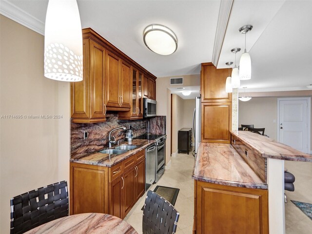 kitchen with decorative backsplash, appliances with stainless steel finishes, a breakfast bar, sink, and hanging light fixtures