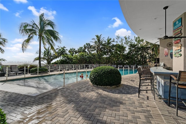 view of swimming pool featuring exterior bar and ceiling fan