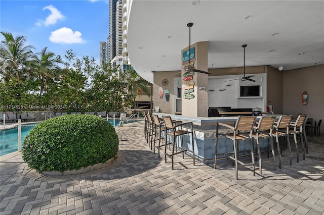 view of patio / terrace featuring ceiling fan, a community pool, and a bar