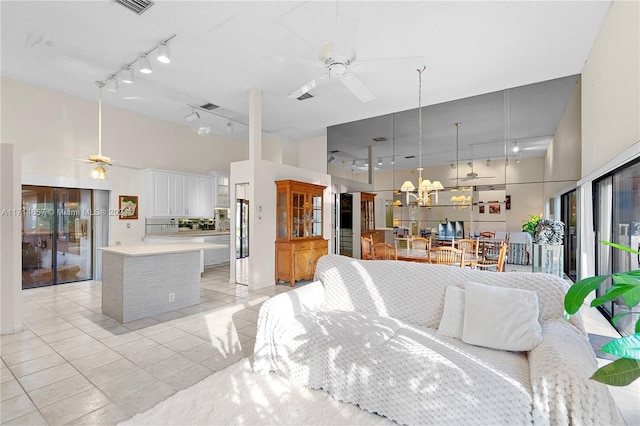 kitchen featuring a center island, white cabinets, ceiling fan, a towering ceiling, and light tile patterned flooring