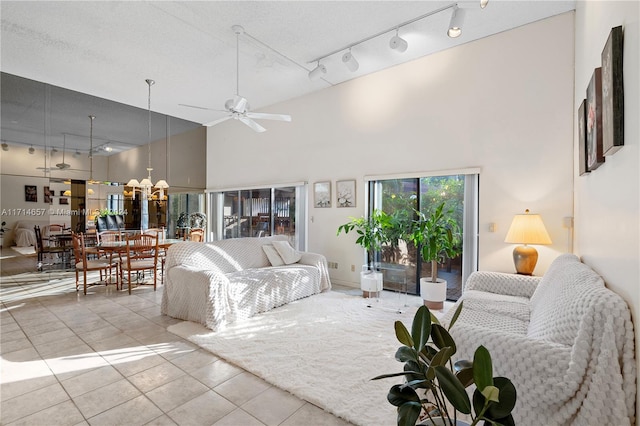 living room with ceiling fan, light tile patterned flooring, a textured ceiling, and high vaulted ceiling