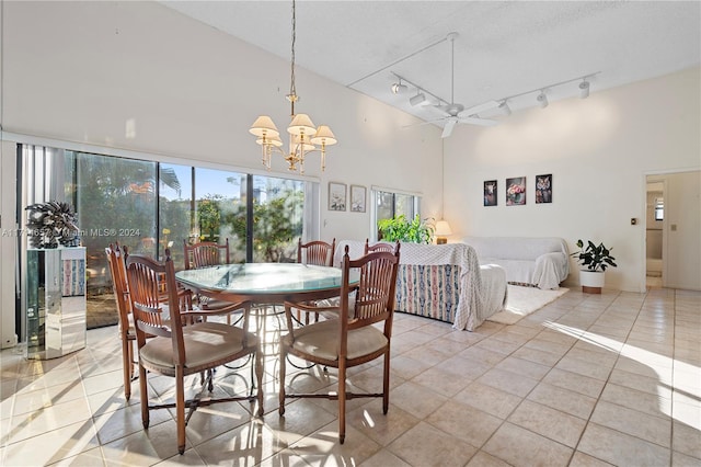 dining space with a textured ceiling, light tile patterned floors, a high ceiling, and ceiling fan with notable chandelier