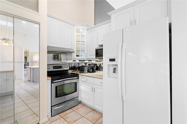 kitchen with a textured ceiling, white cabinetry, stainless steel appliances, and light tile patterned floors