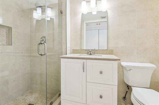 bathroom featuring vanity, tile walls, toilet, and a shower with door