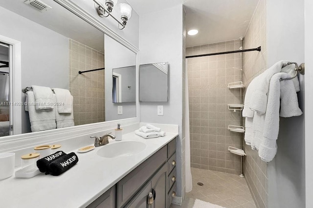 bathroom with a tile shower and vanity