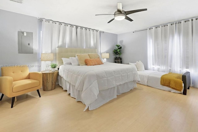 bedroom with multiple windows, hardwood / wood-style floors, electric panel, and ceiling fan