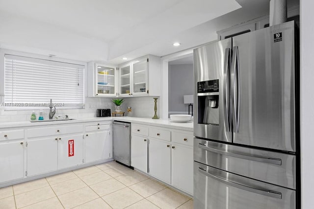 kitchen featuring backsplash, sink, stainless steel refrigerator with ice dispenser, light tile patterned floors, and white cabinetry