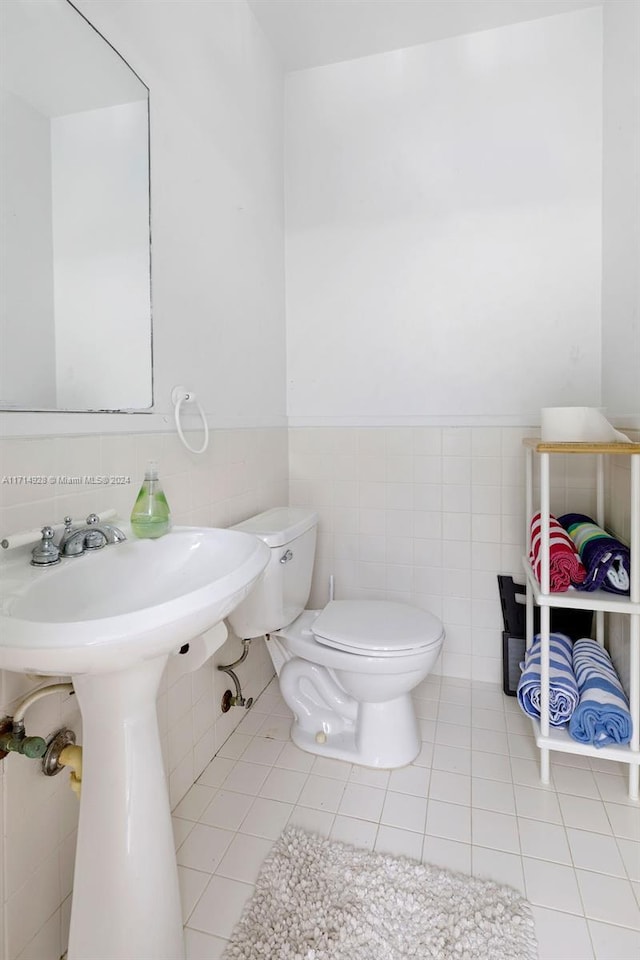 bathroom featuring tile patterned flooring, toilet, and tile walls