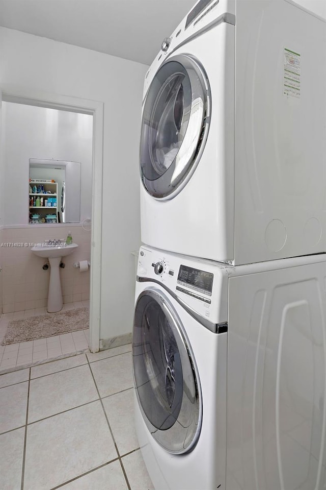 laundry room with stacked washer and dryer and light tile patterned floors