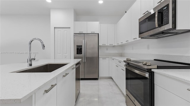 kitchen featuring white cabinetry, sink, light stone counters, and stainless steel appliances