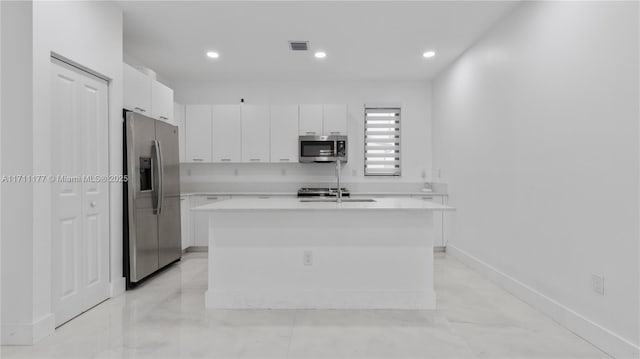 kitchen with stainless steel appliances, white cabinetry, and a kitchen island with sink