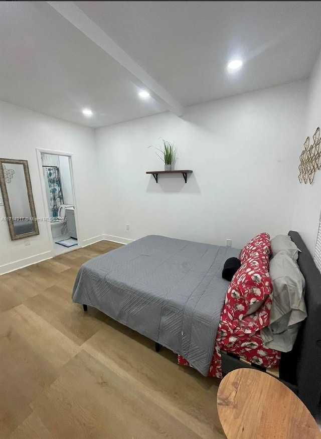 bedroom with connected bathroom, beamed ceiling, and hardwood / wood-style flooring