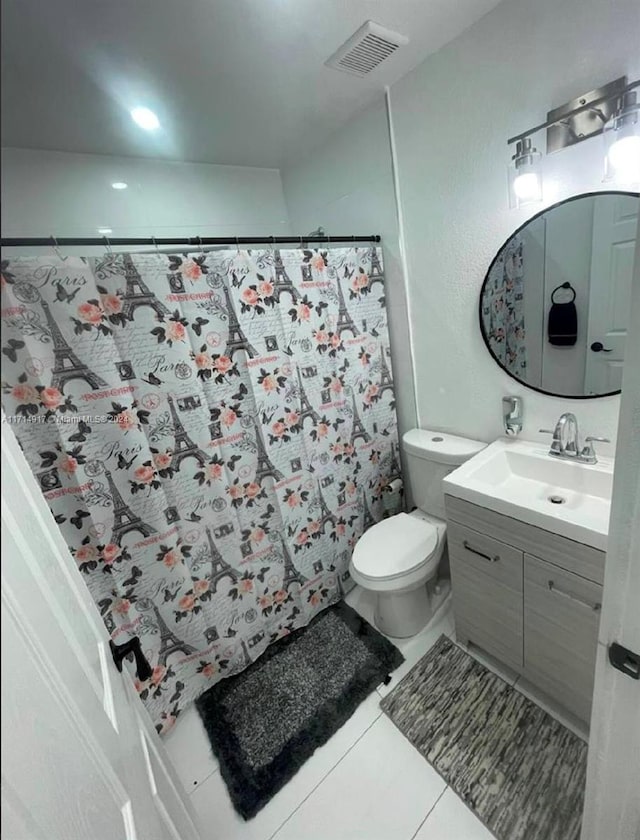 bathroom with tile patterned flooring, vanity, toilet, and walk in shower