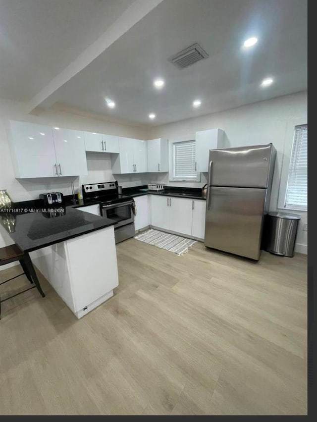 kitchen featuring white cabinets, stainless steel appliances, and light wood-type flooring