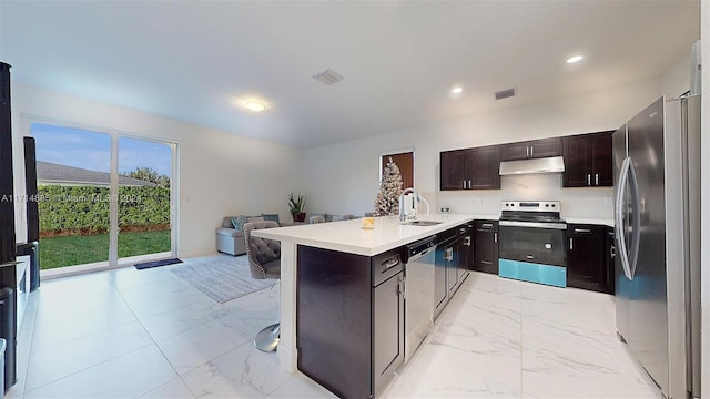 kitchen featuring sink, dark brown cabinets, a kitchen bar, kitchen peninsula, and stainless steel appliances