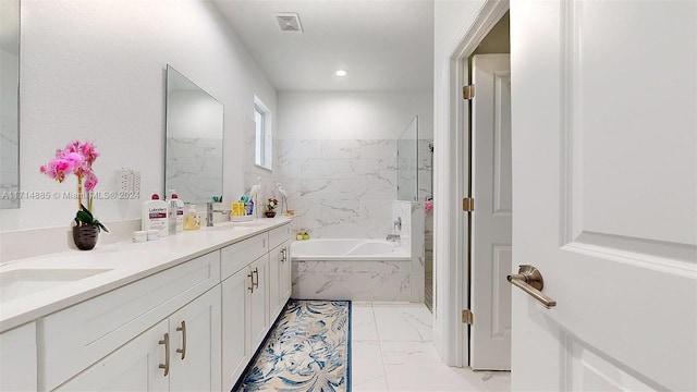 bathroom featuring vanity and a relaxing tiled tub