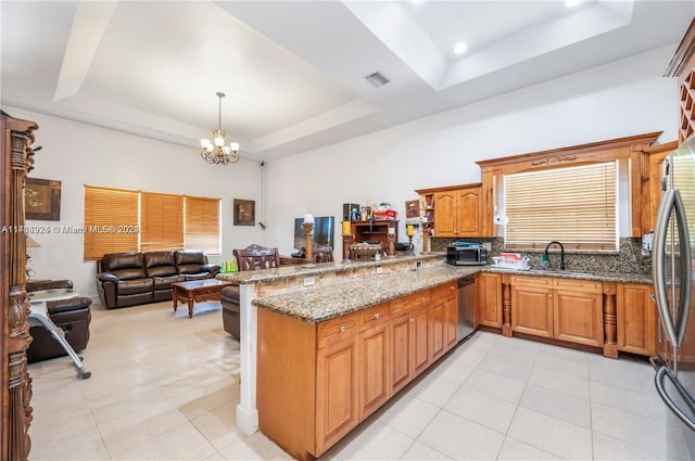 kitchen featuring a raised ceiling, kitchen peninsula, a chandelier, and stainless steel appliances