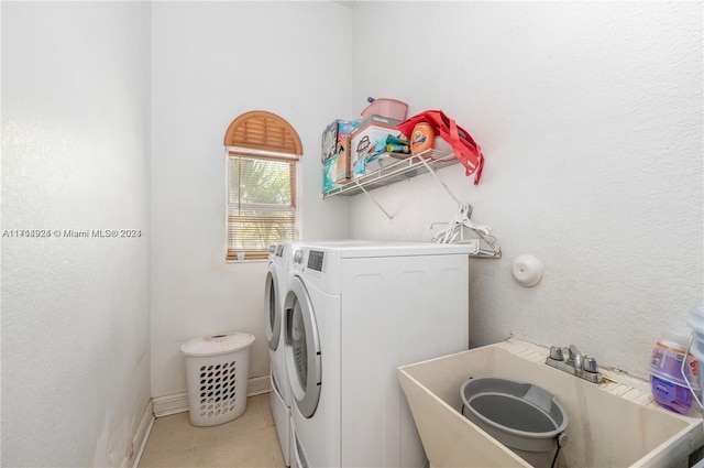 clothes washing area with washer and clothes dryer, light tile patterned floors, and sink