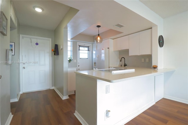 kitchen with kitchen peninsula, decorative light fixtures, white cabinetry, and dark wood-type flooring