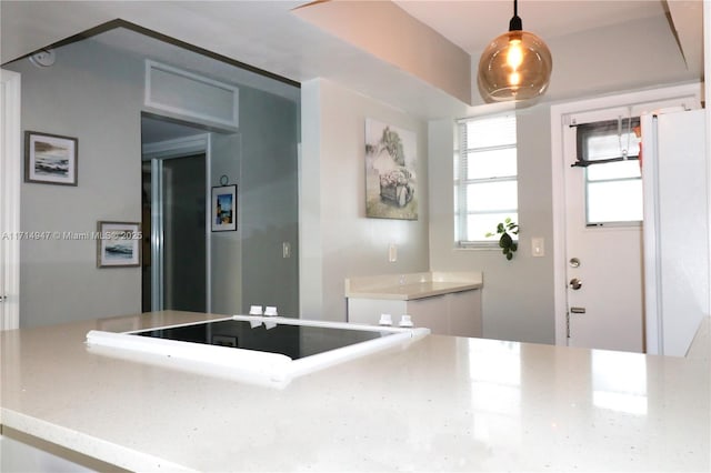 kitchen featuring stovetop, light stone countertops, and hanging light fixtures